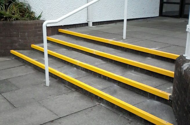 Nez de marche antidérapant jaune sur les marches d'un escalier devant une résidence